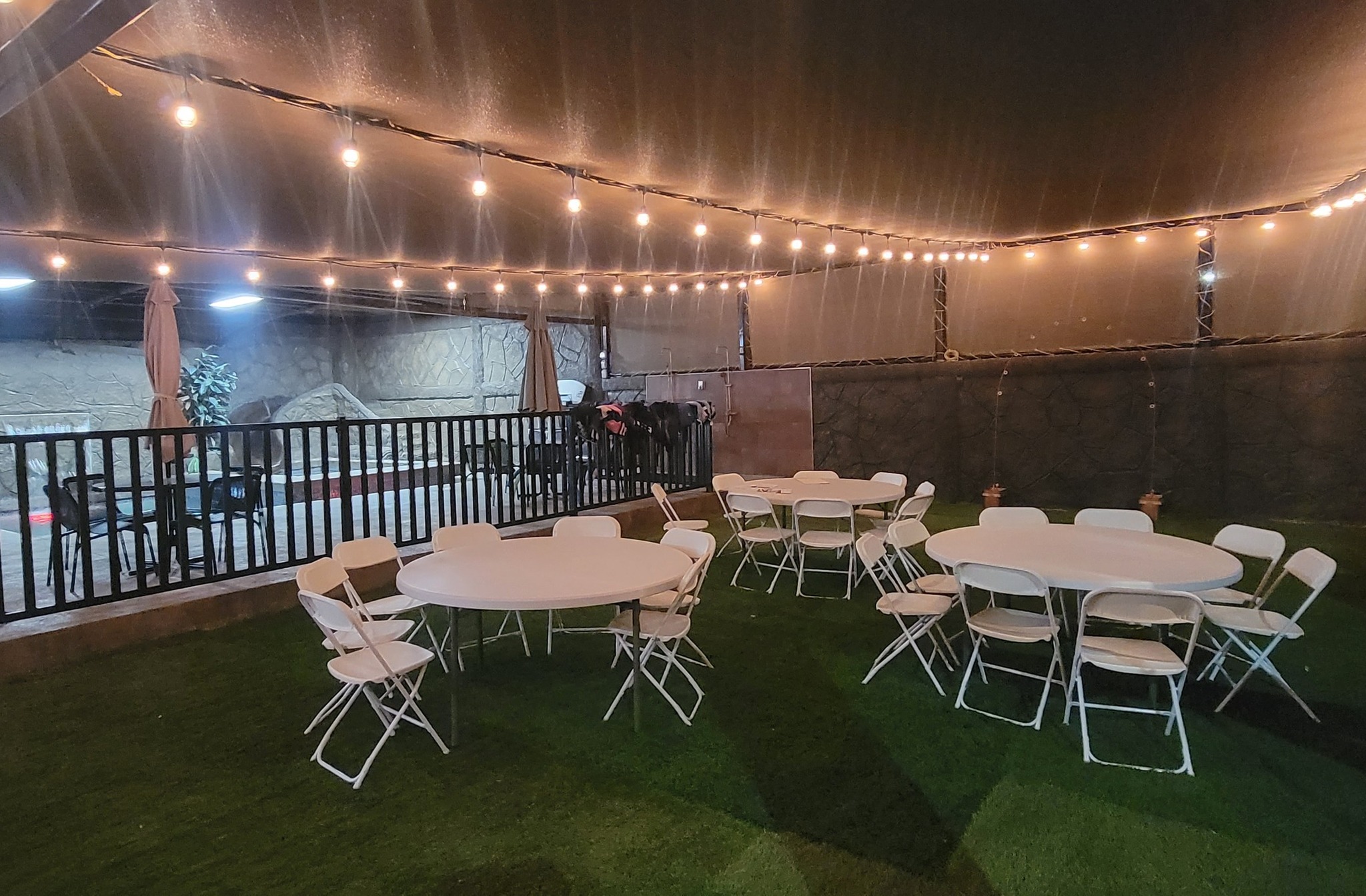 Jardín de noche con luces cálidas y área techada